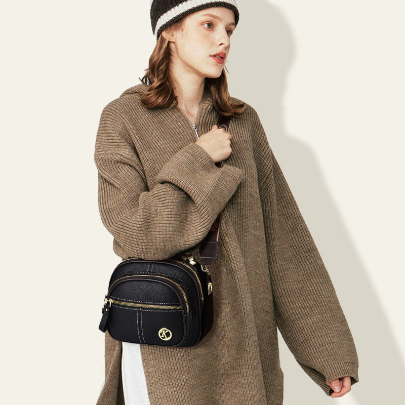 Bolso clásico con múltiples compartimentos, bandolera ancha y ajustable, de cuero.